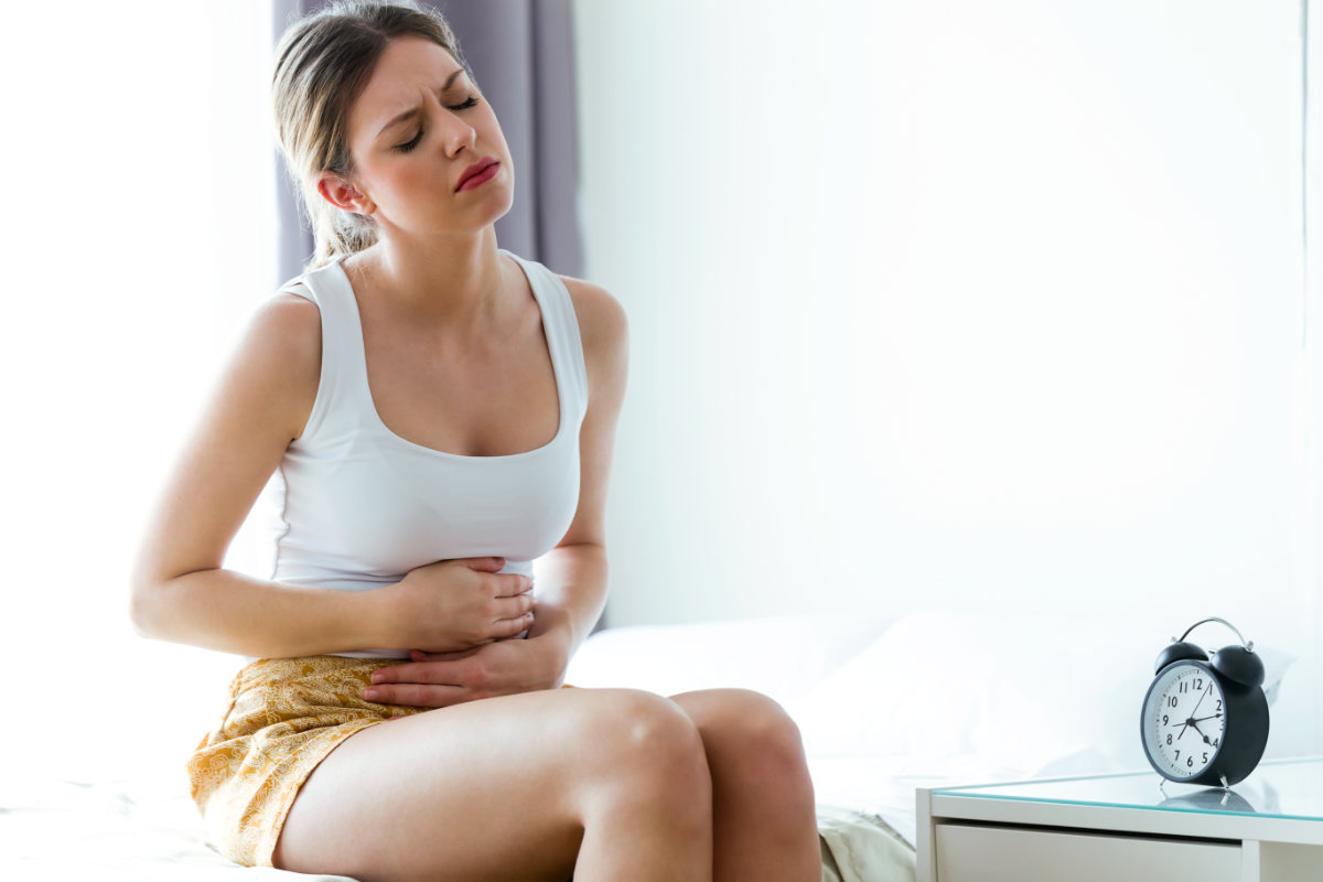 Mujer duele estómago intolerancias sentada en la cama
