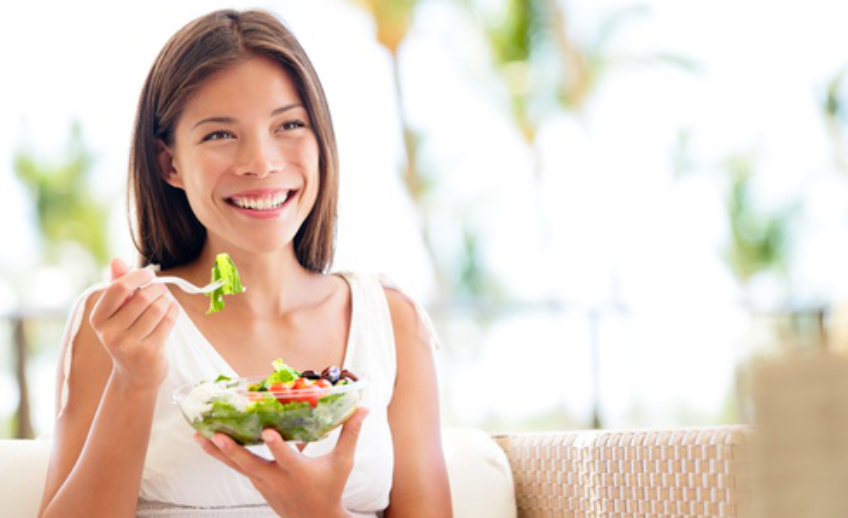 Mujer latina feliz comiendo ensalada casa tratamiento nutrigenético